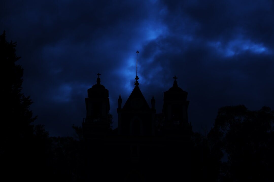 Old dark mansion silhouette under a stormy night sky