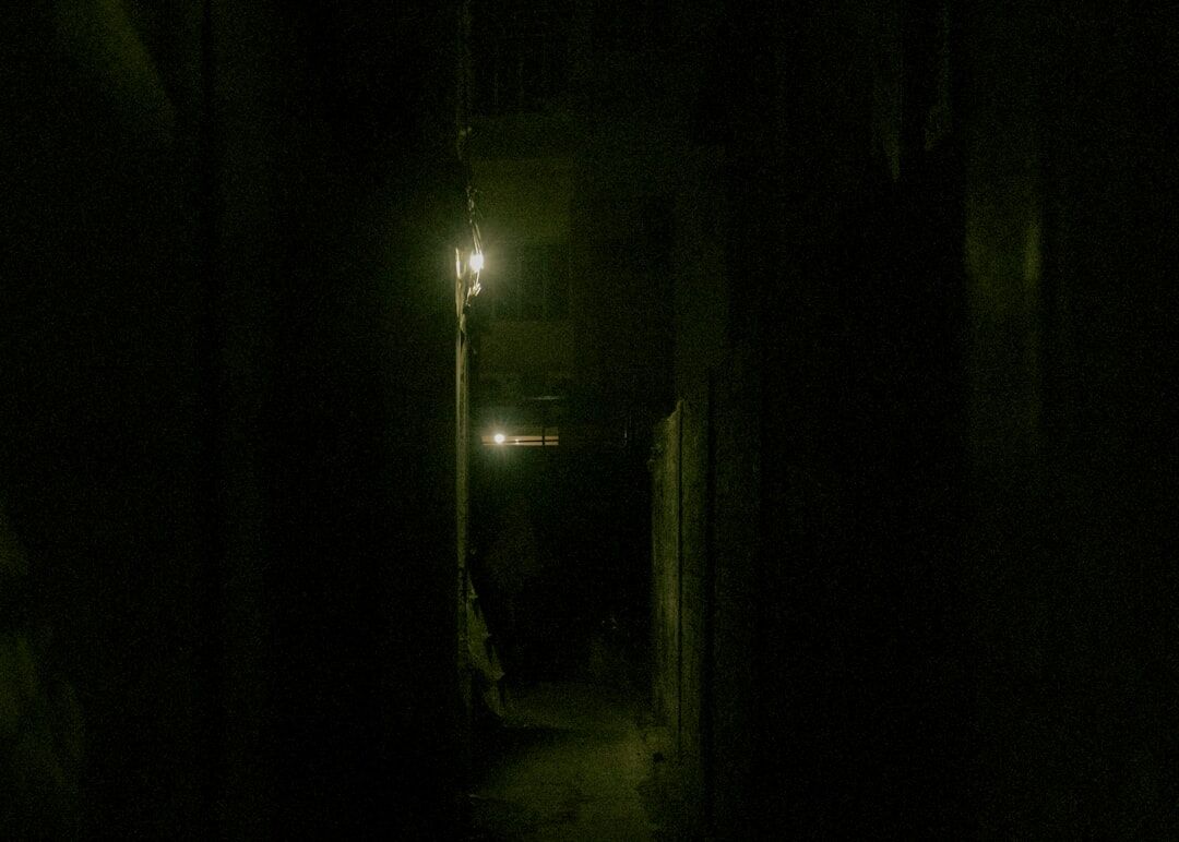 Foggy narrow alley at night lit by a single street lamp